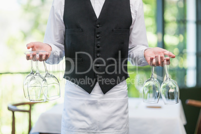 Male waiter holding wine glasses in the restaurant