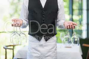 Male waiter holding wine glasses in the restaurant