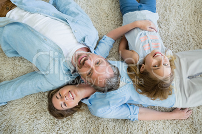 Happy father with his son and daughter lying on carpet