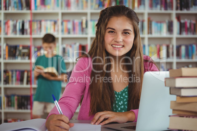 Schoolgirl doing homework in library at school