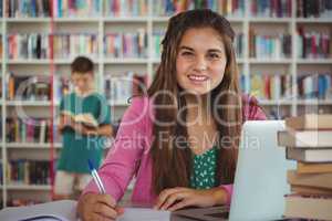 Schoolgirl doing homework in library at school