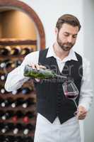 Male waiter pouring wine in wine glass