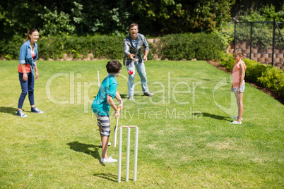 Family playing cricket in park