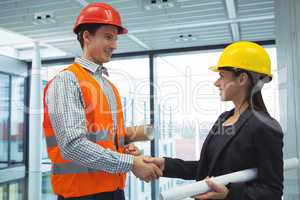 Male architect shaking hands with businesswoman