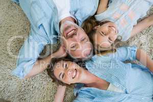 Happy father with his son and daughter lying on carpet