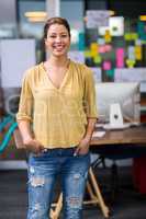 Portrait of smiling female executive standing with hands in pocket