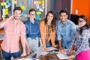 Team of happy graphic designers standing at table