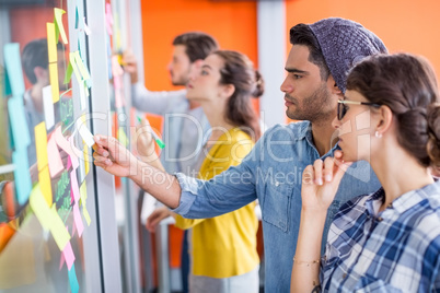 Executives reading sticky notes on glass wall