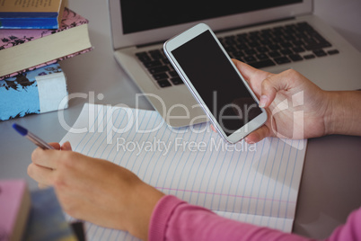 Schoolgirl using mobile phone in library