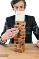 Businessman arranging building blocks with house model on top