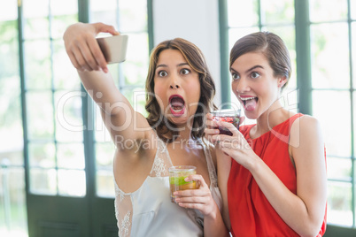 Friends taking a selfie while holding cocktail glasses