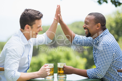 Friends giving high five to each other while having beer