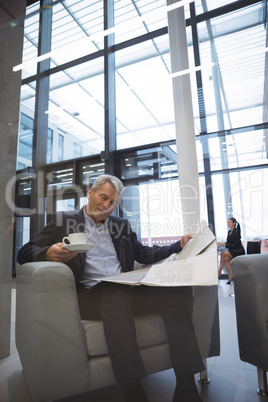 Businessman reading newspaper while having coffee