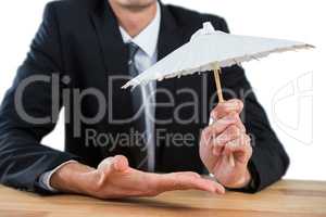 Businessman holding an paper umbrella
