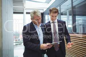 Businesspeople discussing over clipboard in the corridor