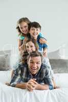 Portrait of smiling family playing on bed in bedroom