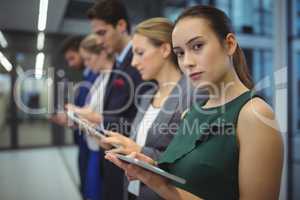 Business executives using electronic devices in corridor