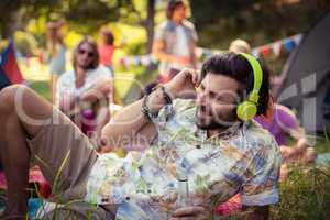 Man in headphones holding beer bottle at campsite