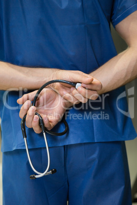 Mid section of male surgeon holding stethoscope