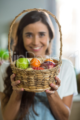 Smiling woman holding a basket of fruits