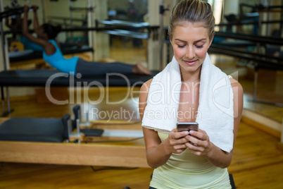 Beautiful fit woman using mobile phone after workout