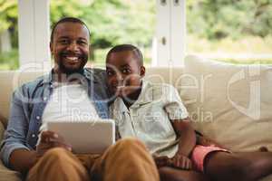 Portrait of father and son using laptop in living room