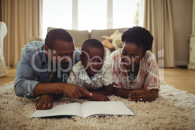 Parents and son reading a book while lying on a rug