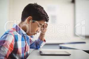 Schoolboy using digital tablet at desk