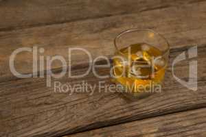 Glass of whisky with ice on wooden table