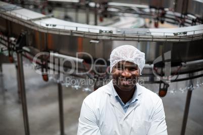 Smiling factory engineer standing in bottle factory