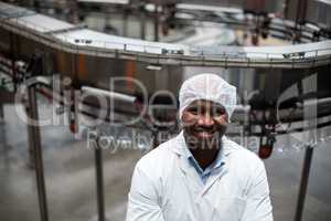 Smiling factory engineer standing in bottle factory