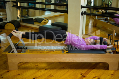 Determined woman practicing stretching exercise on reformer