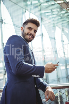 Smiling businessman using mobile phone at railway station