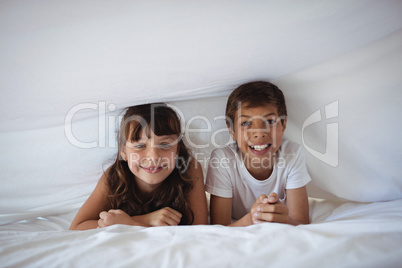 Siblings smiling under the bed sheet