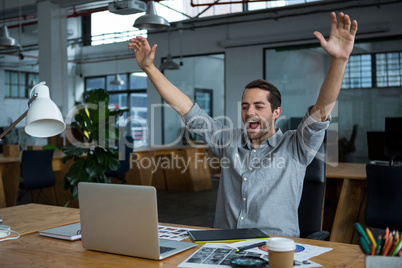 Excited man sitting with laptop at desk