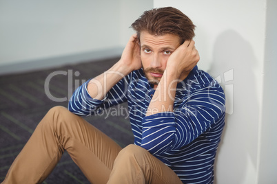 Portrait of sad business executive sitting against wall