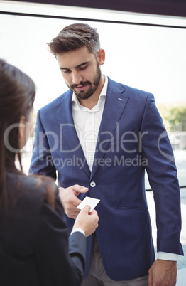 Businesswoman giving visiting card to businessman