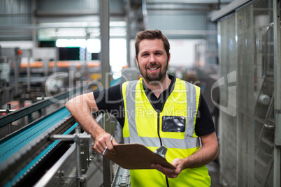 Portrait of factory worker standing with clipboard