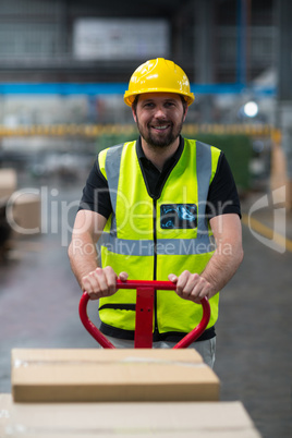 Factory worker pulling trolley of cardboard boxes