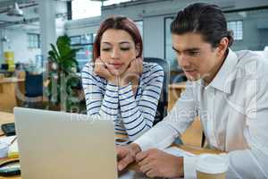 Man and woman working on laptop at desk