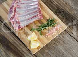 Beef ribs, rosemary herb, salt and lemon on wooden board