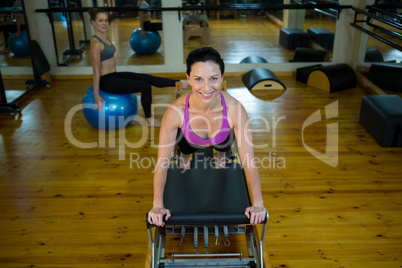 Portrait of happy woman practicing stretching exercise on reformer