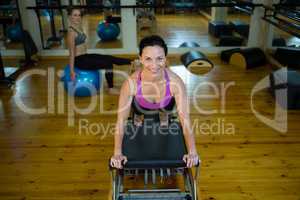 Portrait of happy woman practicing stretching exercise on reformer