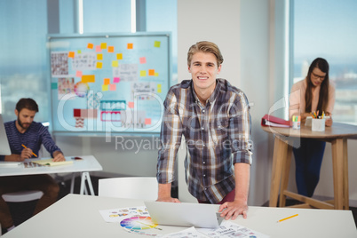 Portrait of male graphic designer leaning on table