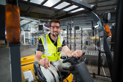 Portrait of smiling factory worker driving forklift