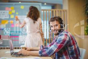 Portrait of business executive listening song while using laptop