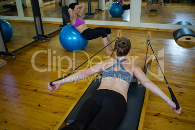 Determined woman practicing stretching exercise on reformer