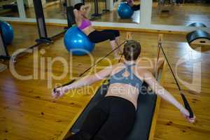 Determined woman practicing stretching exercise on reformer