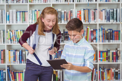 Happy students using digital tablet in library