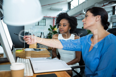 Female graphic designer pointing on desktop pc